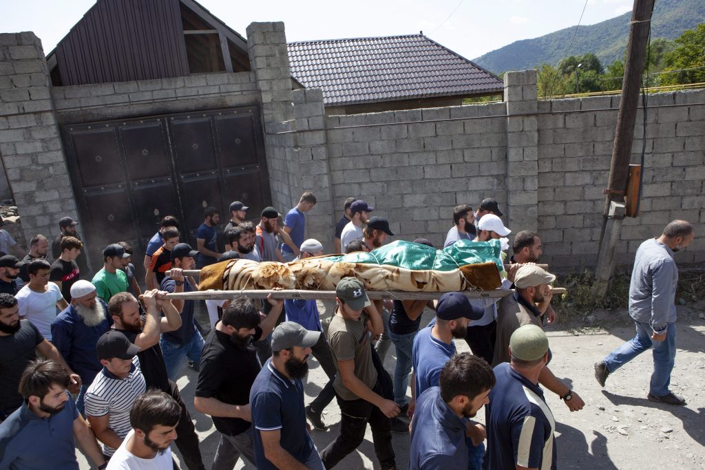 FILE-In this Aug. 29, 2019 file photo people carry the body of the victim who has been identified as Zelimkhan Khangoshvili, a Georgian Muslim during the funeral in Duisi village, the Pankisi Gorge valley, in Georgia. 