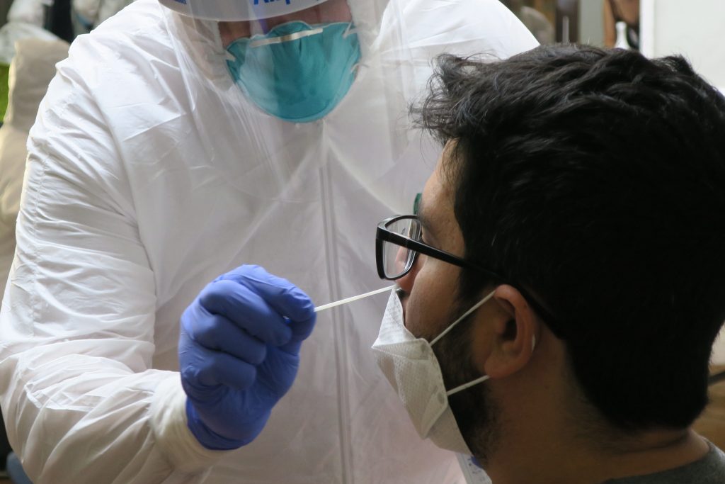A lab technician inserts a swab into a resident's nose as part of the test for coronavirus, in San Juan, Puerto Rico.