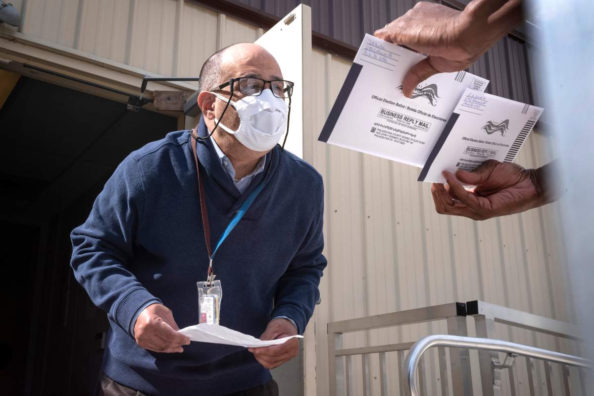 An employee of the Philadelphia Commissioners Office examines ballots at a satellite election office at Overbrook High School on Thursday, Oct. 1, 2020, in Philadelphia.