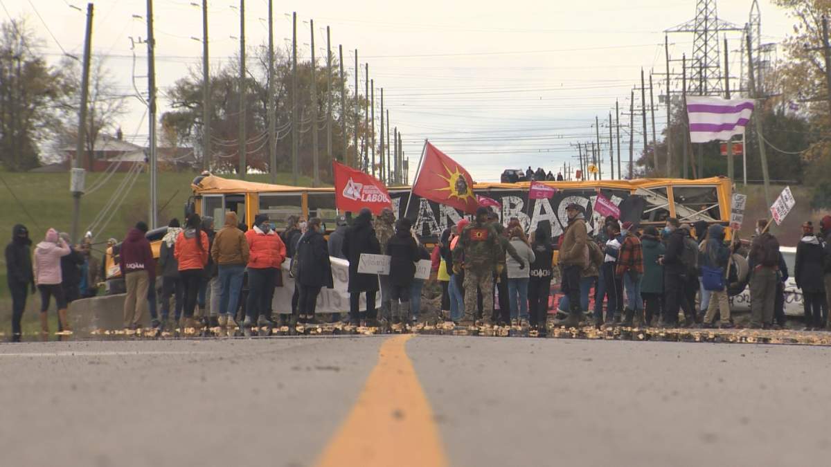 Supporters marching to police barricades on Oct. 25, 2020 chanting "land back", with Caledonia residents looking on.