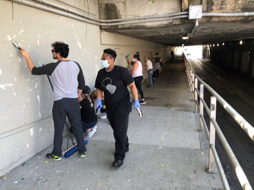 Volunteers scratching off the old paint on the Richmond Street Underpass. (Melanie Schambach/Provided)