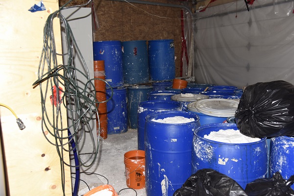 Blue barrels and black garbage bags containing waste by-products.
