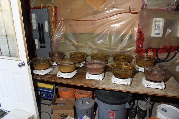 Wooden folding table holding glass cooking vessels on hot plates at a massive drug lab in Lumby, B.C. 