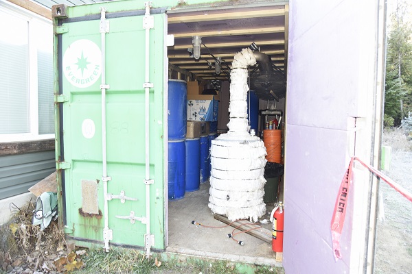 Blue barrels and a distiller inside a shipping container.