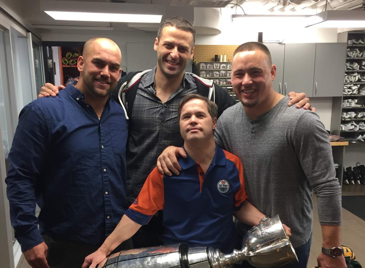 Joey Moss holds the Grey Cup with then EE Football Team members Ryan King (L), Mike Reilly (C) and J.C. Sherritt (R).