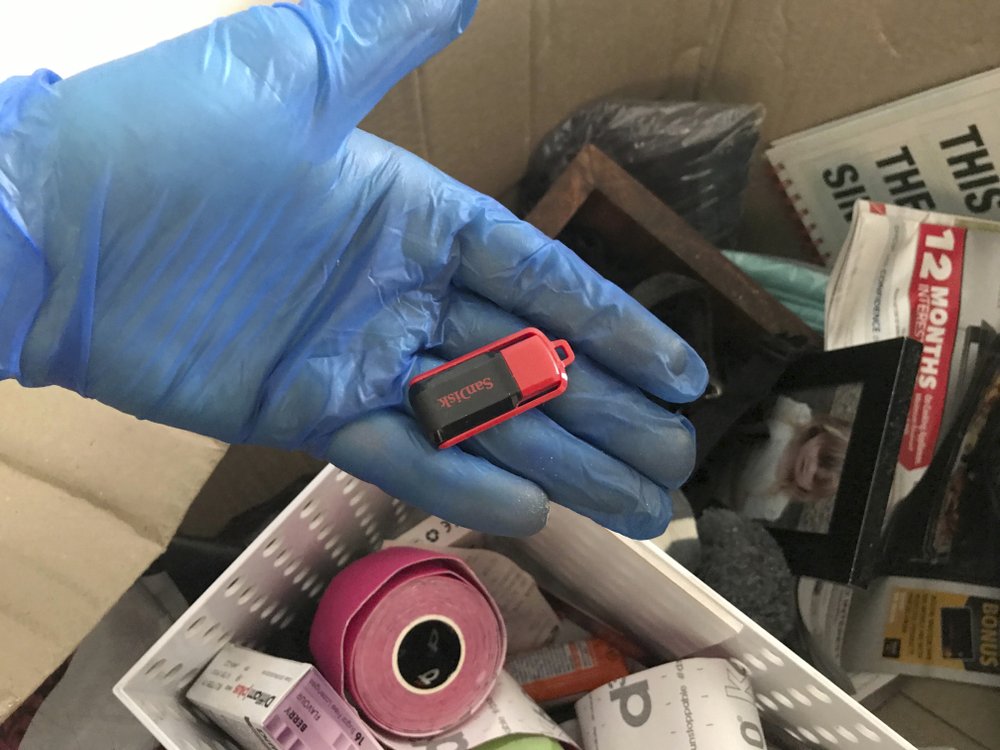 In this undated photo provided by the New South Wales Police, an investigator holds a thumb drive which is part of seized material collected while investigating a major child sex abuse ring. A childcare worker and a children's soccer coach were among 16 men arrested in the Australian states of New South Wales, Queensland and Western Australia in recent months on 828 charges of sexually abusing children, producing and distributing child abuse material and bestiality, Australian Federal Police Assistant Commissioner Justine Gough said Wednesday, Nov. 11, 2020. 