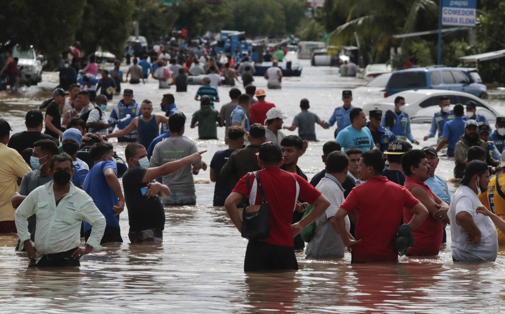 Residents wade through a flooded road in the aftermath of Hurricane Eta in Planeta, Honduras, Thursday, Nov. 5, 2020. The storm that hit Nicaragua as a Category 4 hurricane on Tuesday had become more of a vast tropical rainstorm, but it was advancing so slowly and dumping so much rain that much of Central America remained on high alert.