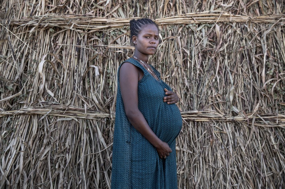 Ethiopian Amhara refugee Blaines Alfao Eileen, 8-months pregnant and who fled the conflict in Ethiopia, stands near her shelter, at Um Rakuba refugee camp in Qadarif, eastern Sudan, Monday, Nov. 23, 2020.