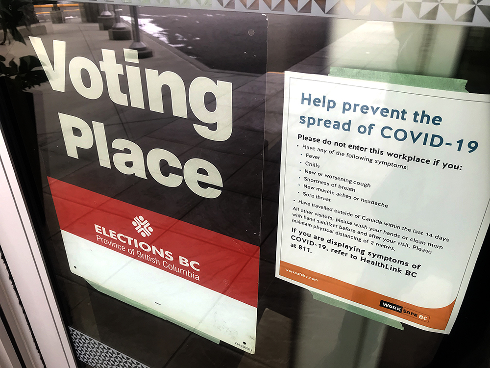 An Elections BC sign alongside a COVID-19 sign during the 2020 general election in B.C., on Oct. 24, 2020.