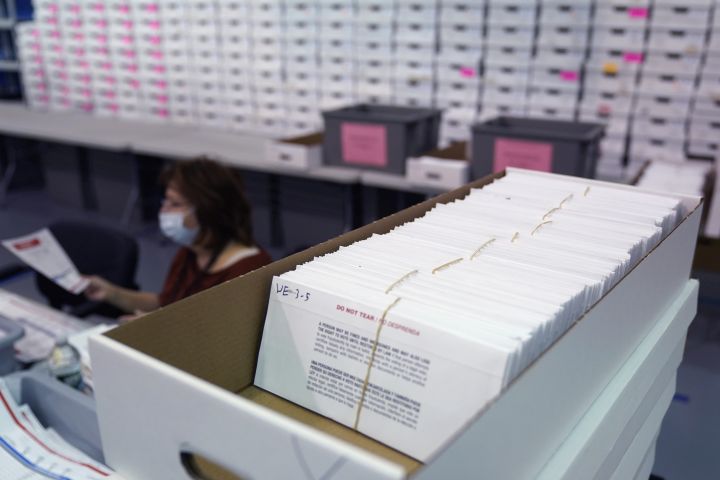 A Board of Election's employee works among stacks of mail-in ballots in Linden, N.J., Thursday, Oct. 29, 2020. 