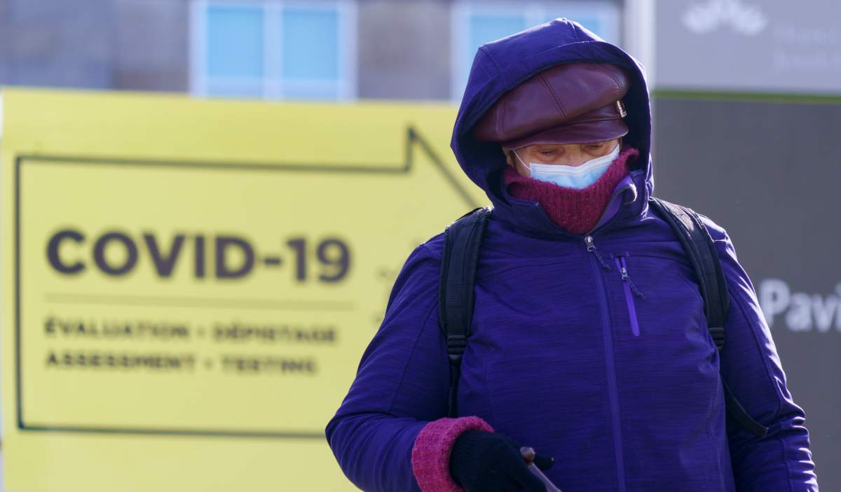 A woman all bundled up walks past a COVID-19 test clinic during a brisk fall morning in Montreal, on Friday, Oct. 30, 2020. 