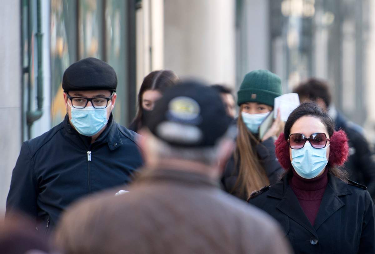 People wear face masks as they cross a street in Montreal, Saturday, October 31, 2020, as the COVID-19 pandemic continues in Canada and around the world. 