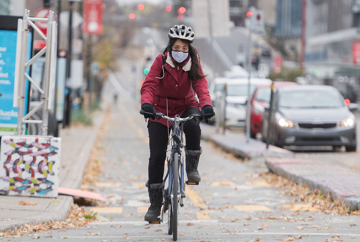A woman wears a face mask as she cycles in Montreal, Sunday, November 1, 2020, as the COVID-19 pandemic continues in Canada and around the world. 