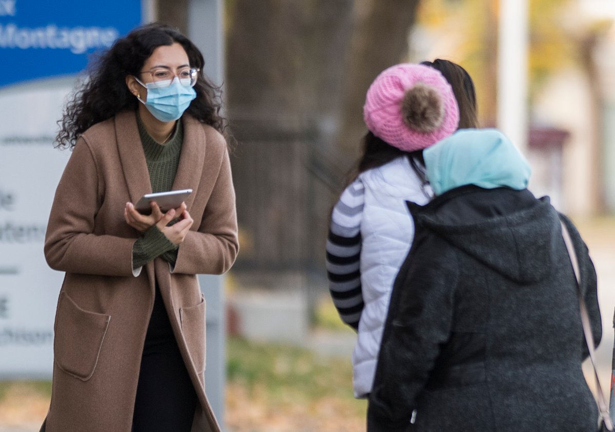 A health-care worker talks to people as they wait to be tested for COVID-19 at a testing clinic in Montreal, Sunday, Oct. 25, 2020, as the COVID-19 pandemic continues in Canada and around the world. 