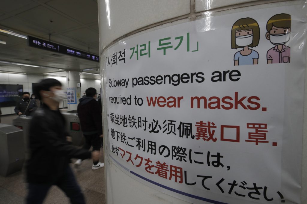 People wearing face masks as a precaution against the coronavirus, walk past a banner at a subway station in Seoul, South Korea, Friday, Nov. 13, 2020. South Korea has reported its biggest daily jump in COVID-19 cases in 70 days as the government began fining people who fail to wear masks in public. From Friday, officials started to impose fines of up to 100,000 won ($90) for people who fail to properly wear masks in public transport and a wide range of venues, including hospitals, nursing homes, pharmacies, nightclubs, karaoke bars, religious and sports facilities and at gatherings of more than 500 people. 