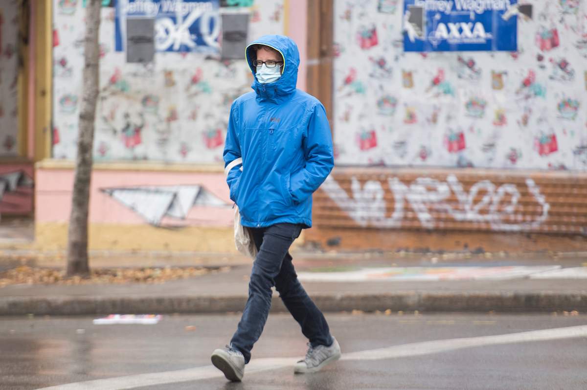 A man wears a face mask as he crosses a street in Montreal, Sunday, November 15, 2020, as the COVID-19 pandemic continues in Canada and around the world.THE CANADIAN PRESS/Graham Hughes.