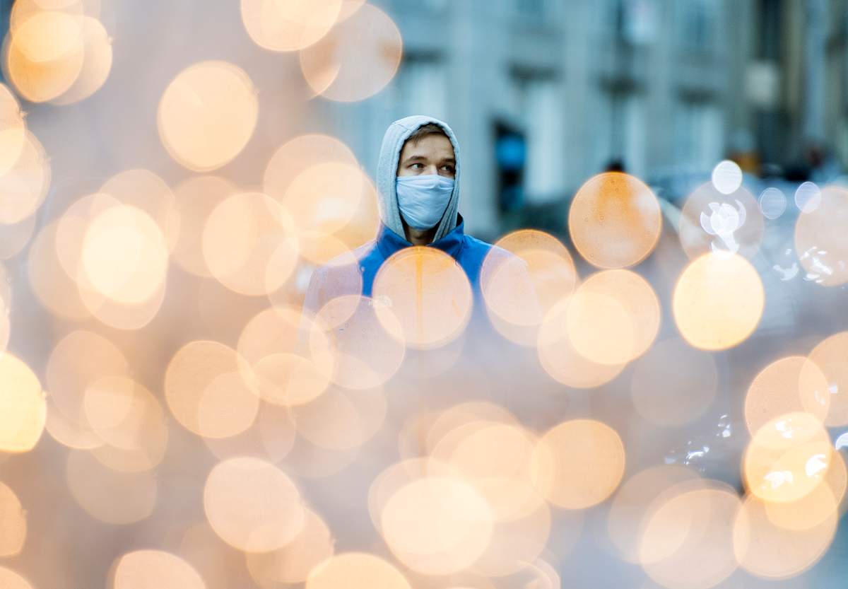 A man wears a face mask as he walks by festive lights in Montreal, Saturday, Nov. 21, 2020, as the COVID-19 pandemic continues in Canada and around the world. 