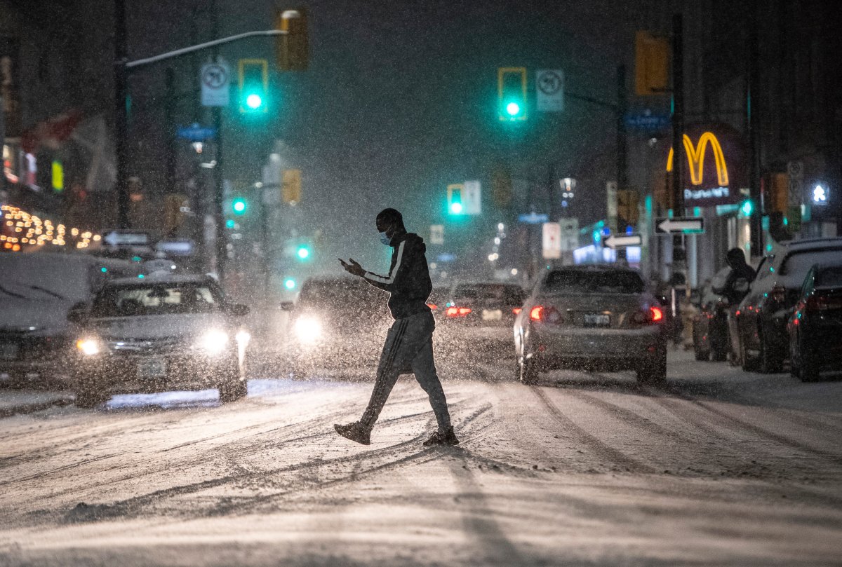 A person crosses Elgin Street as snow falls in Ottawa, on Sunday, Nov. 22, 2020. 