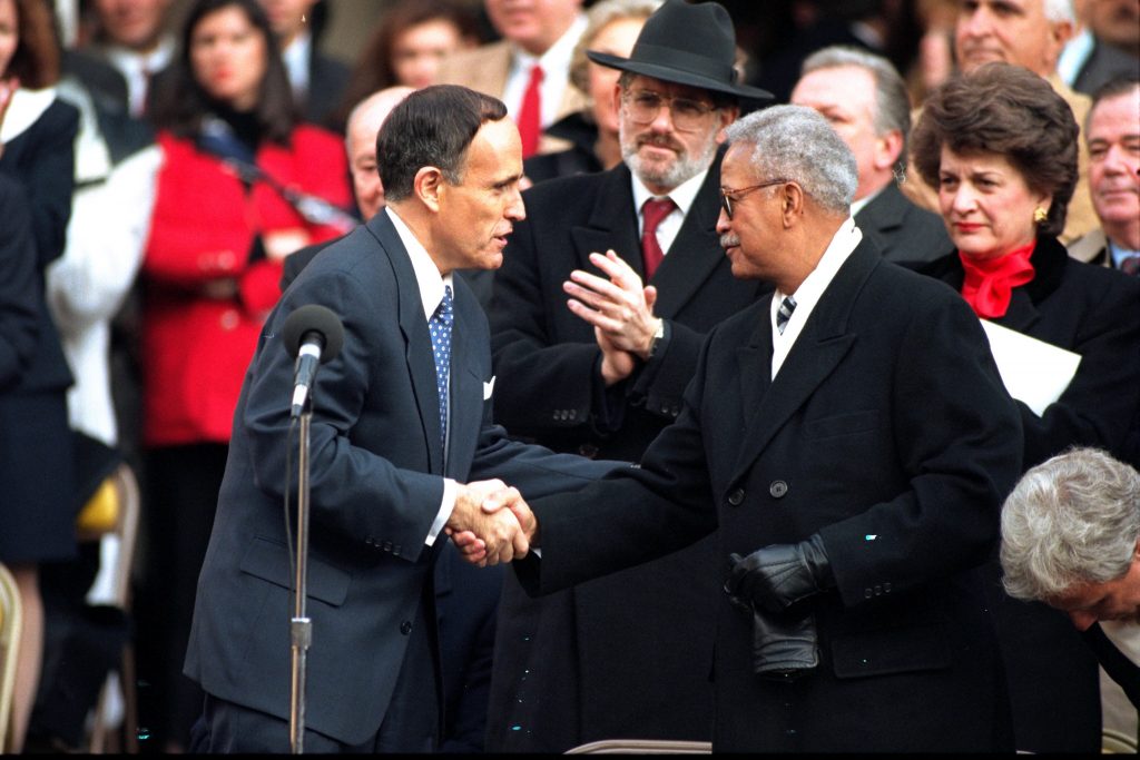 FILE – In this Jan. 2, 1994, file photo, New York Mayor Rudolph Giuliani, left, shakes hands with outgoing mayor David Dinkins during inaugural ceremonies at City Hall in New York. Dinkins, New York City’s first African-American mayor, died Monday, Nov. 23, 2020. He was 93. (AP Photo/Mark Lennihan, File)