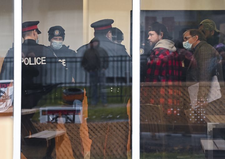 Adam Skelly, second right, owner of Adamson Barbecue, talks with police inside his restaurant after defying provincial lockdown orders to shut down indoor and outdoor dining during the COVID-19 pandemic in Toronto.