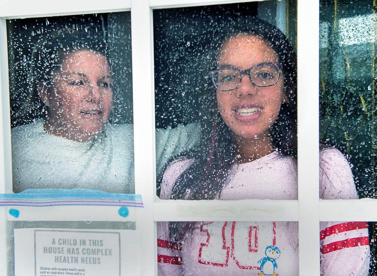 Lisa Ali and her 15-year-old daughter Tahlia look out from the front door of their Halifax-area home in Cole Harbour, N.S., on March 24, 2020. THE CANADIAN PRESS/Andrew Vaughan.