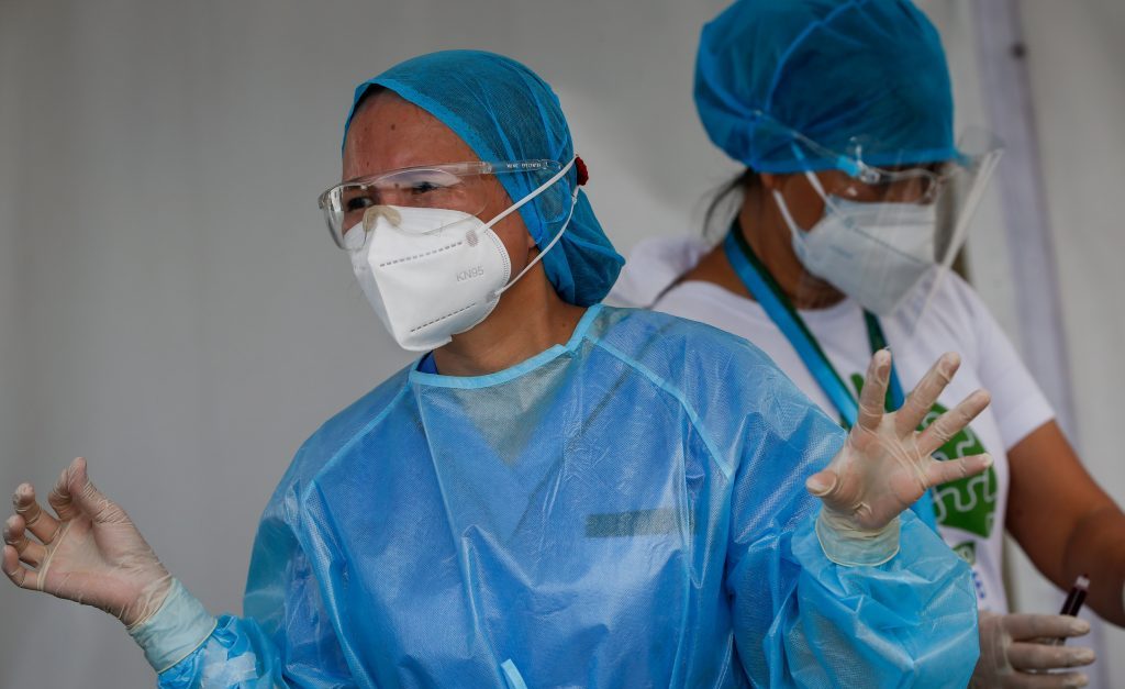A health worker reacts after extracting blood from a patient at a drive-thru COVID-19 testing center in Manila, Philippines, 03 August 2020. 