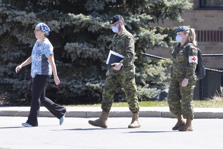 A staff member escorts members of the Canadian Armed Forces in to a long term care home, in Pickering, Ont. on Saturday, April 25, 2020.