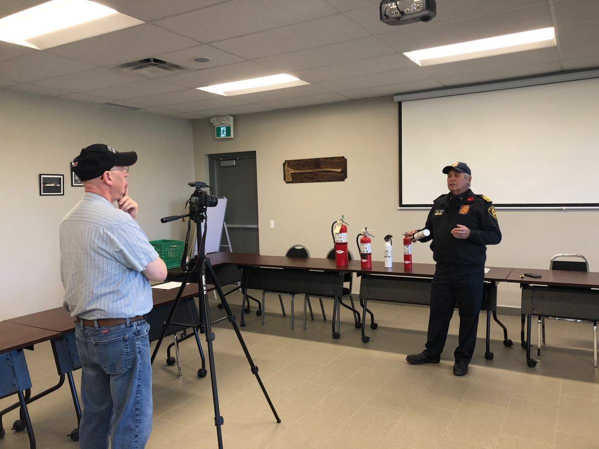 Tony Bendel (left) and St. Thomas Fire Department’s chief fire prevention officer Bill Todd film an instructional video about having fire extinguishers in vehicles.