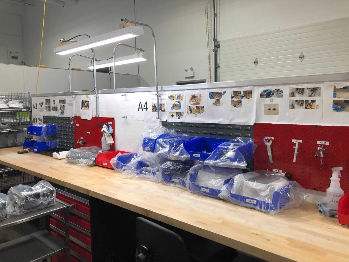 One of many ventilator workstations that had to be constructed at JMP Solutions. Hanging on the red wall to the right are specialized tools designed for ventilator assembly.