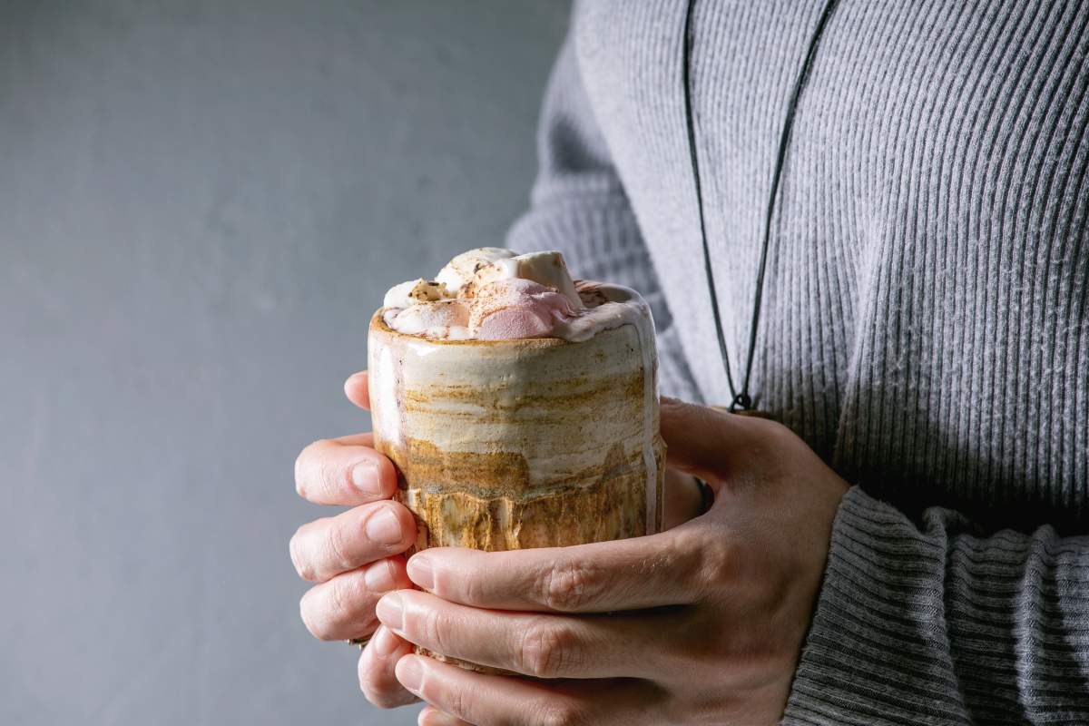 Woman in grey sweater hold in hands ceramic mug with hot chocolate or cocoa with marshmallow.