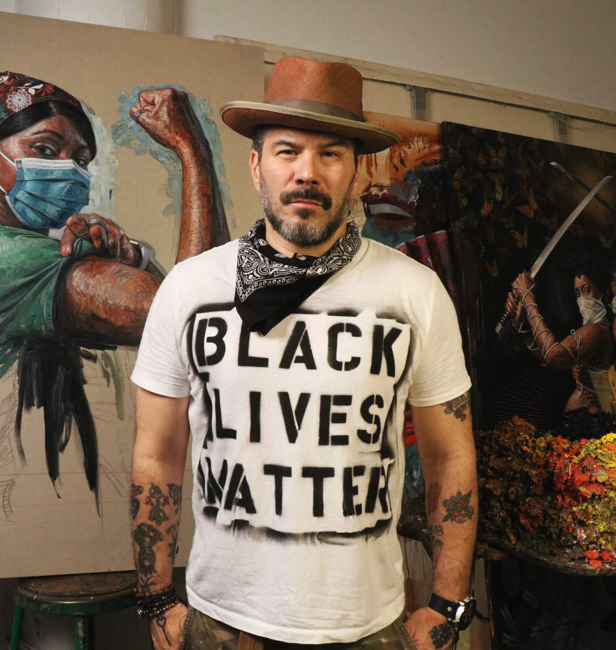 Tim Okamura poses in front of a portrait