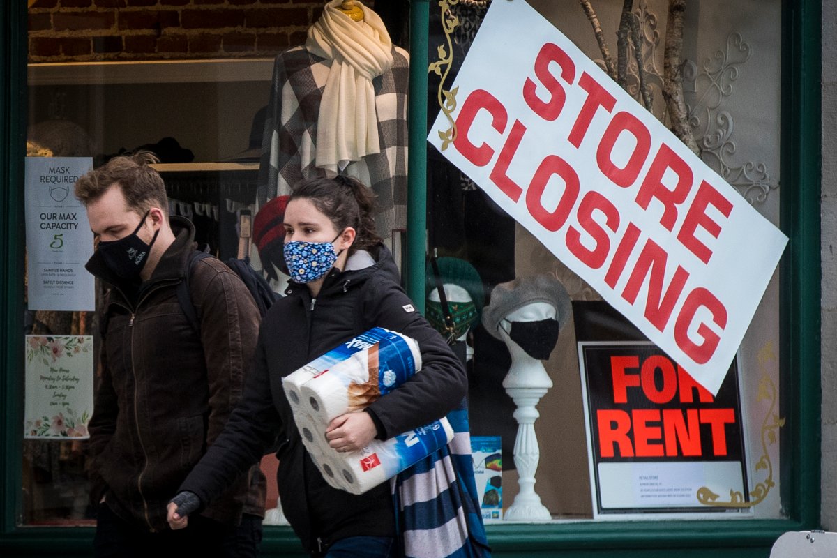 People wears masks as they walk past a store that is closing in Kingston, Ontario on Monday, November 16, 2020, as the COVID-19 pandemic continues across Canada and around the world. 
