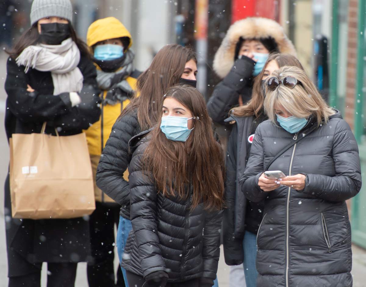 Pedestrians protect themselves from the cold and COVID-19 as they wait for a light to change, Tuesday, November 3, 2020  in Montreal.
