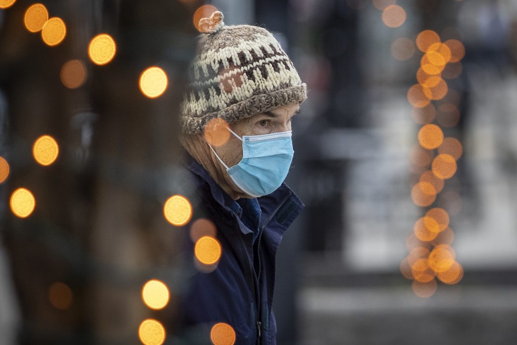 A person wears a mask, while framed through Christmas lights in Kingston, Ontario on Monday, November 23, 2020, as the COVID-19 pandemic continues across Canada and around the world. THE CANADIAN PRESS IMAGES/Lars Hagberg.