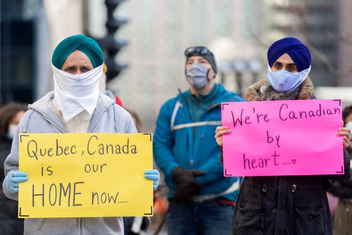 People take part in a demonstration outside Quebec Premier Francois Legault’s office in Montreal, Saturday, Nov. 21, 2020, where they called on the government to give permanent residency status to all migrant workers and asylum seekers. The COVID-19 pandemic continues in Canada and around the world. 