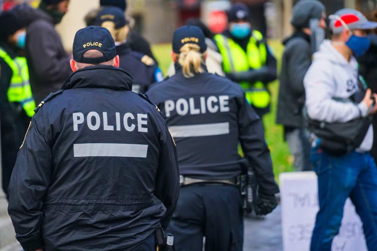 Montreal police officers watching to see if people are respecting social-distancing at a protest in Montreal, Saturday, Nov. 28, 2020. 