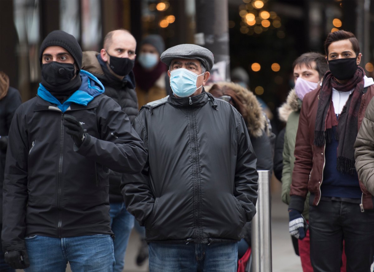People wear face masks as they walk along a street in Montreal, Saturday, December 5, 2020, as the COVID-19 pandemic continues in Canada and around the world. 