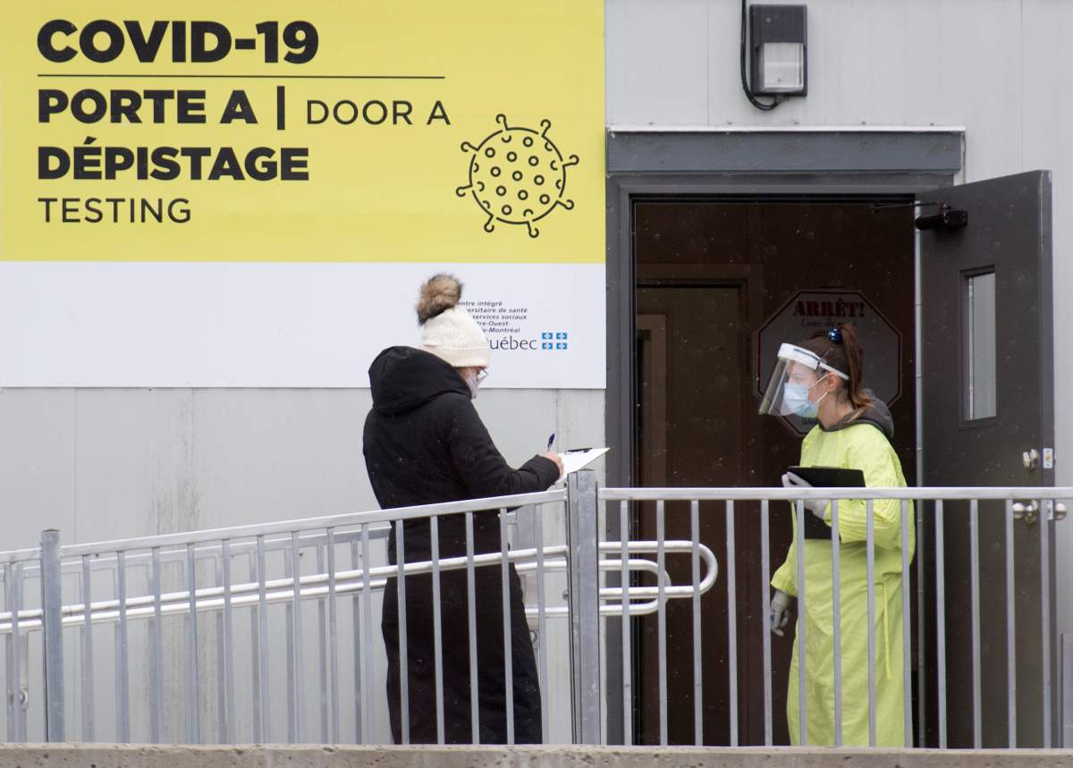 A health-care worker talks to a woman as she waits to be tested for COVID-19 at a testing clinic in Montreal, Sunday, Dec. 6, 2020, as the COVID-19 pandemic continues in Canada and around the world.