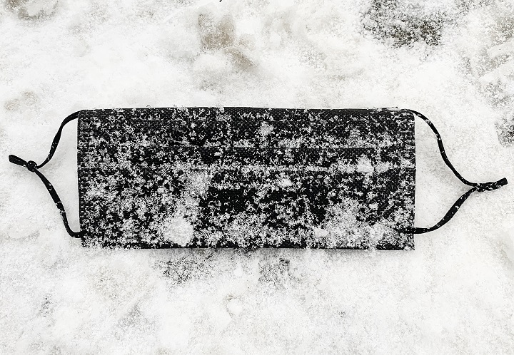 A discarded black face mask is shown on a street following snowfall in Montreal, Wednesday, Dec. 9, 2020, as the COVID-19 pandemic continues in Canada and around the world. 