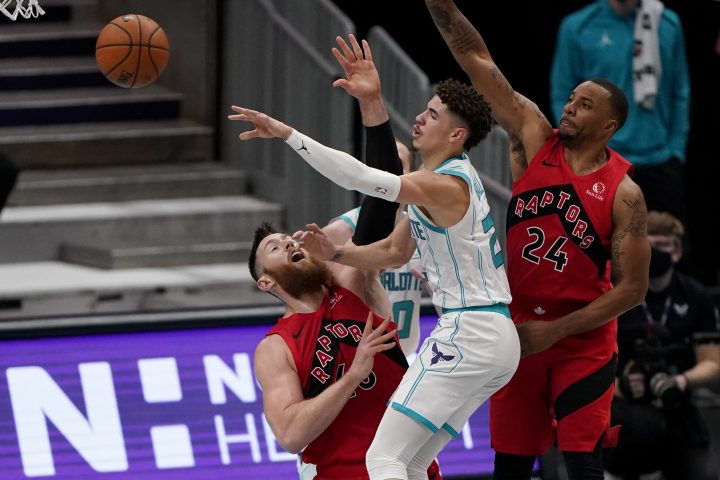 Charlotte Hornets guard LaMelo Ball, center, fouls Toronto Raptors' Aron Baynes, left, during the first half of an NBA preseason basketball game in Charlotte, N.C., on Saturday, Dec. 12, 2020.