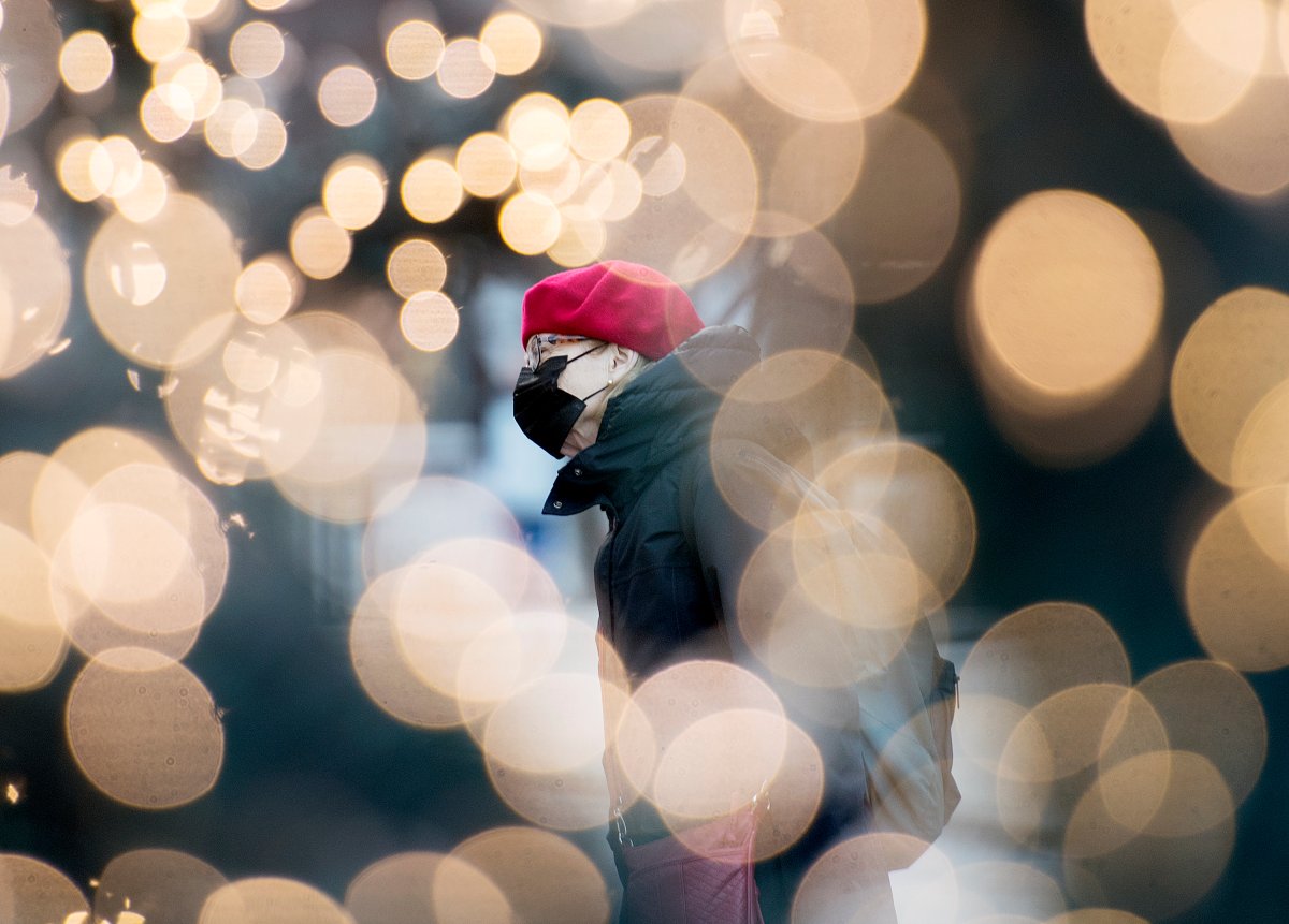 A woman wears a face mask as she's framed amongst festive lights on a street in Montreal, Saturday, Nov. 21, 2020, as the COVID-19 pandemic continues in Canada and around the world. 