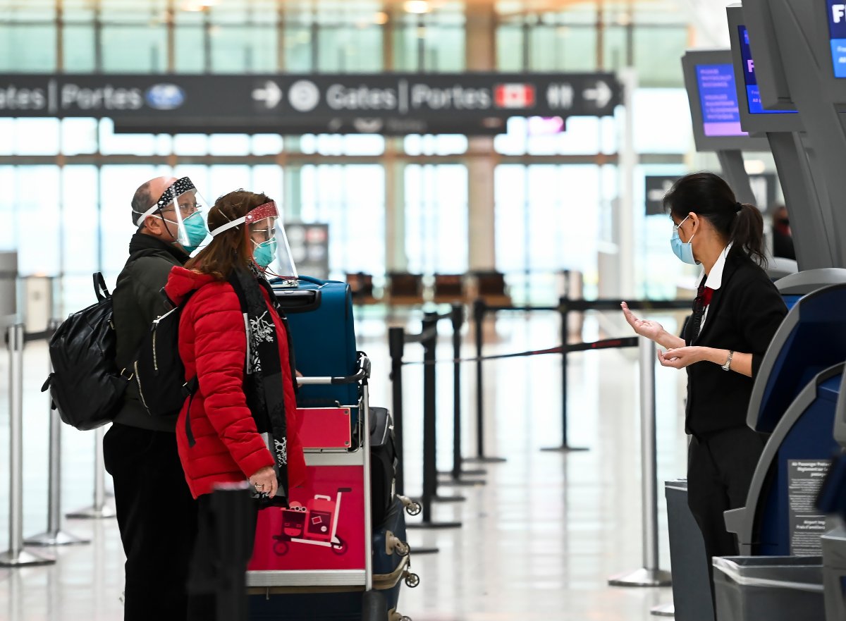 People wearing protective equipment check in at the international departures at Pearson International Airport during the COVID-19 pandemic in Toronto on Monday, December 14, 2020. International travellers will now have to pay for a COVID-19 test if required.