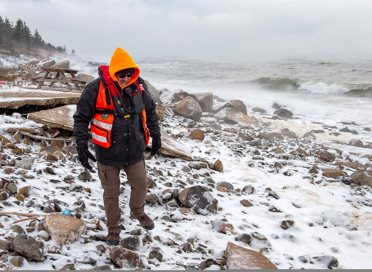 A member of a ground search and rescue team walks along the shore of the Bay of Fundy in Hillsburn, N.S. as they continue to look for five fishermen missing after the scallop dragger Chief William Saulis sank in the Bay of Fundy, on Wednesday, Dec. 16, 2020. RCAF search and rescue aircraft and Canadian Coast Guard boats have been dispatched as well.