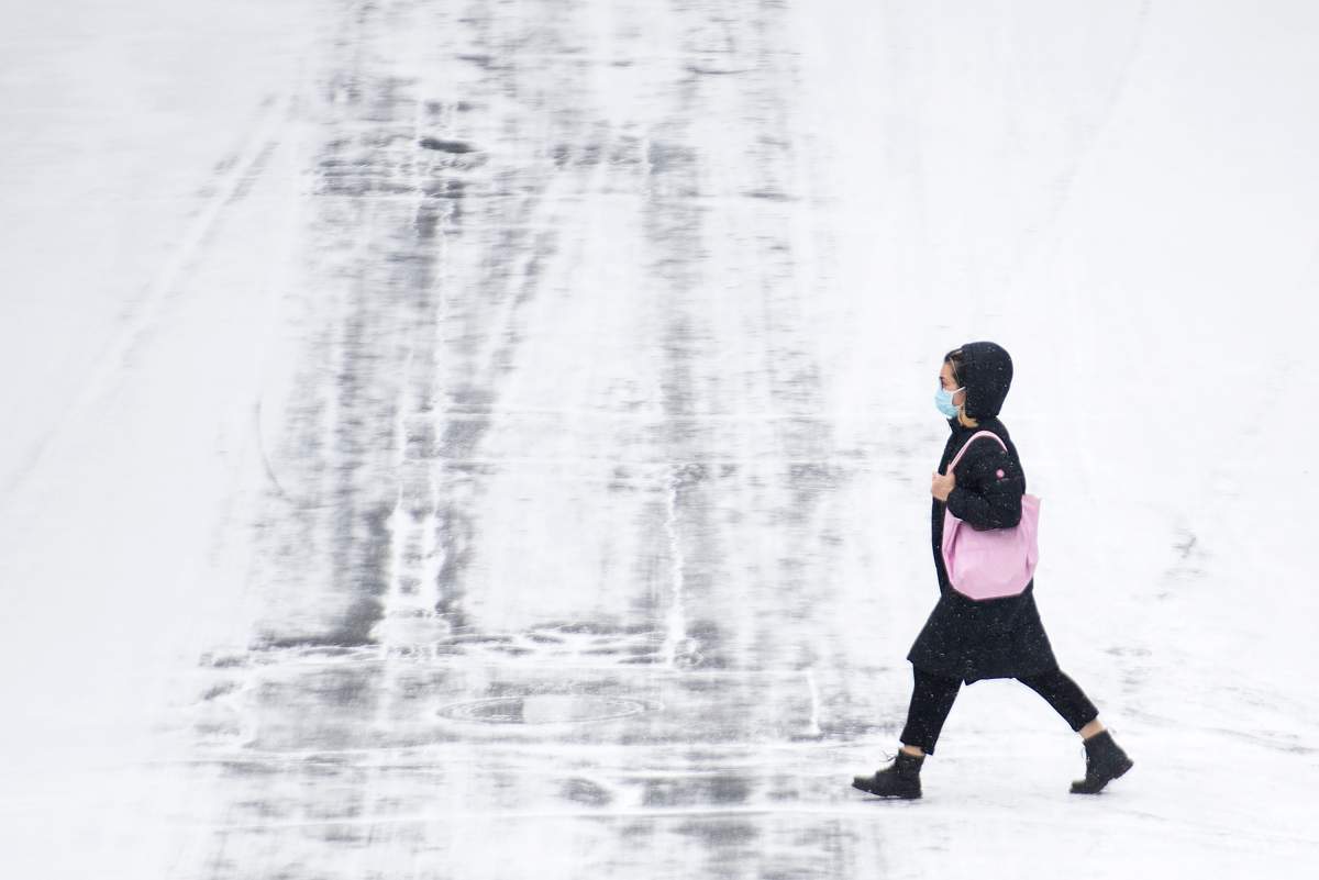 A woman wears a face mask as she crosses a street on Boxing Day in Montreal, Saturday, Dec. 26, 2020, as the COVID-19 pandemic continues in Canada and around the world. 