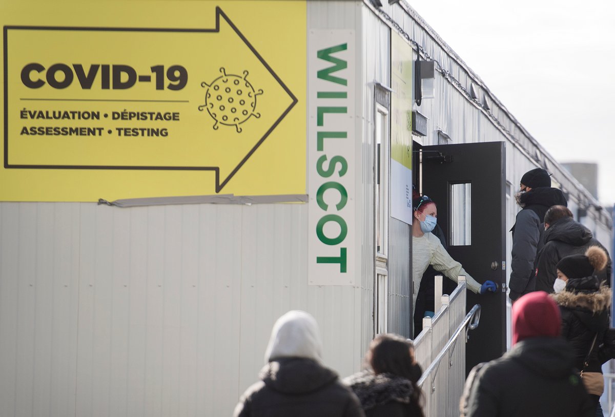 A healthcare worker talks with people as they wait to be tested for COVID-19 at a clinic in Montreal, Sunday, Dec. 27, 2020, as the COVID-19 pandemic continues in Canada and around the world. 