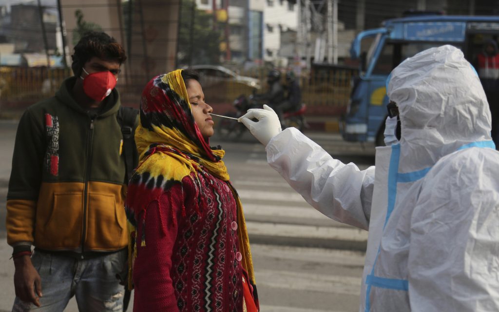 A health worker collects a swab sample from a woman to test for COVID-19 in Jammu, India. (AP Photo/Channi Anand)