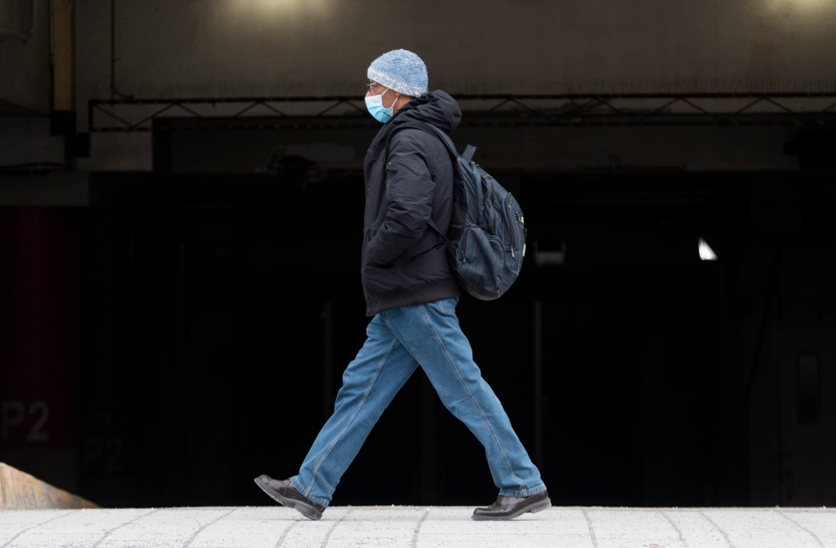A man wears a face mask as he walks along a street in Montreal, Wednesday, December 30, 2020, as the COVID-19 pandemic continues in Canada and around the world. 