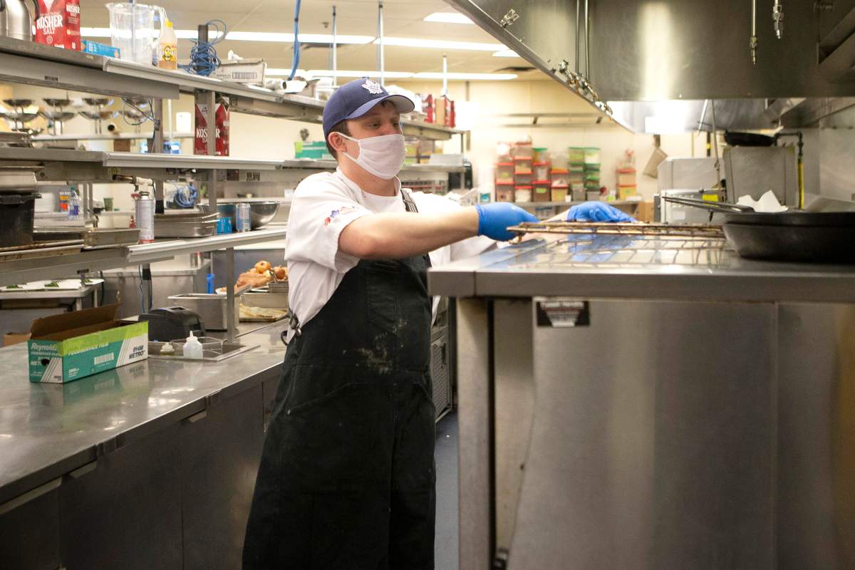 An MLSE employee works in the kitchen at the Scotiabank Arena, making meals which are packaged in the stadium's arena floor, in Toronto on Wednesday, April 22, 2020. The meals are being donated as part of an initiative with partners such as Second Harvest, and are being distributed to front-line workers and homeless shelters during the COVID-19 pandemic.