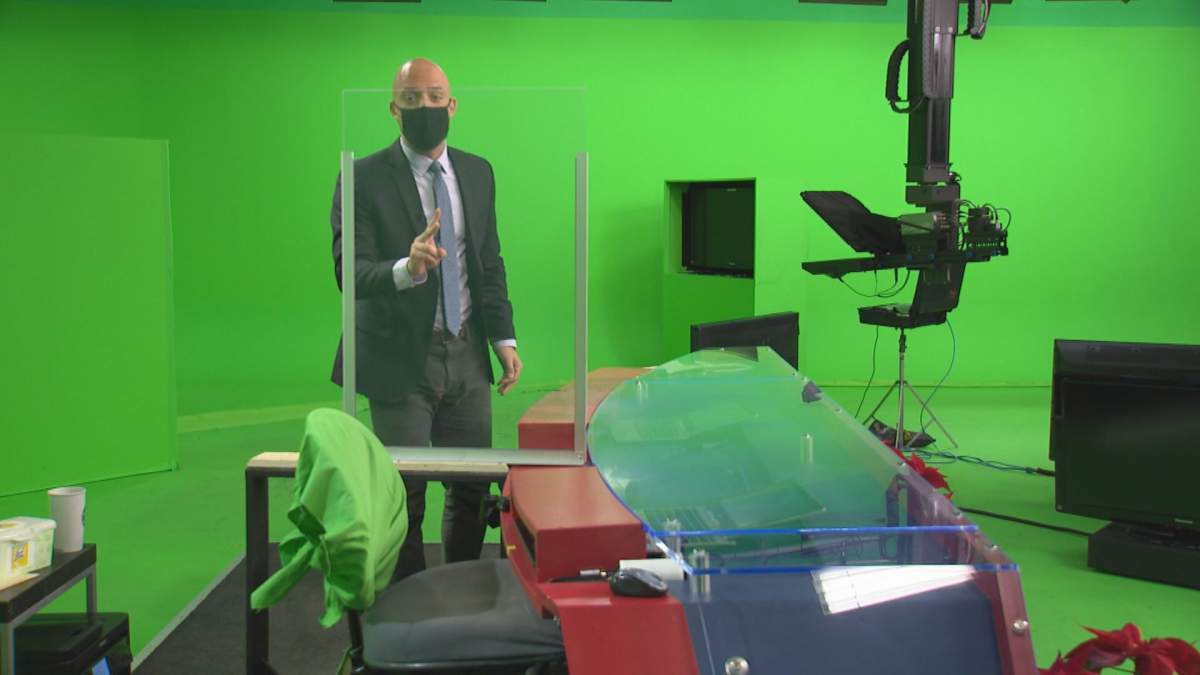 Global News’ anchor Joel Senick highlights one of the many COVID-19 safety measures in place at Global Calgary — a plastic barrier on the news desk.