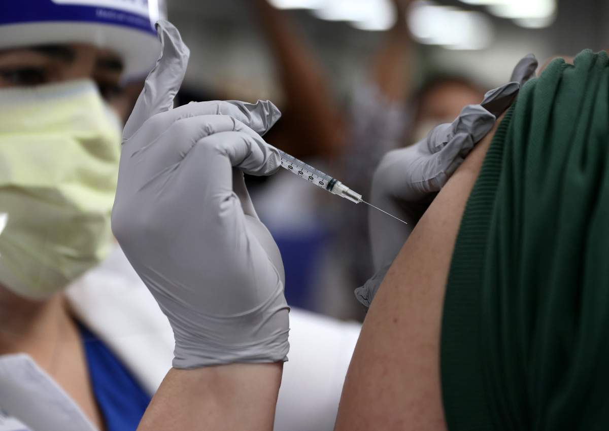 MIAMI, FLORIDA - DECEMBER 15: Susana Flores Villamil, RN at Jackson Health Systems administers a Pfizer-BioNtech COVID-19 vaccine to a healthcare worker on December 15, 2020 in Miami, Florida.  Jackson Memorial Hospital began the vaccination of frontline healthcare workers joining with hospital systems around the country as the COVID-19 vaccine is rolled out. (Photo by Joe Raedle/Getty Images).